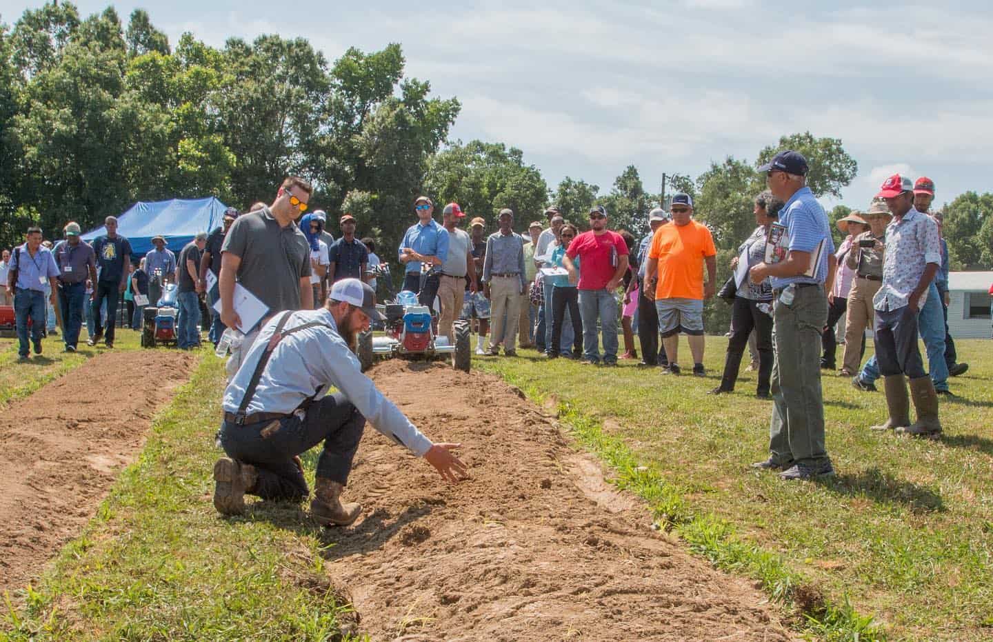 Farmers and community members participating in a soil health workshop outdoors. Soil health workshop with farmers and community members in an outdoor farm setting.
